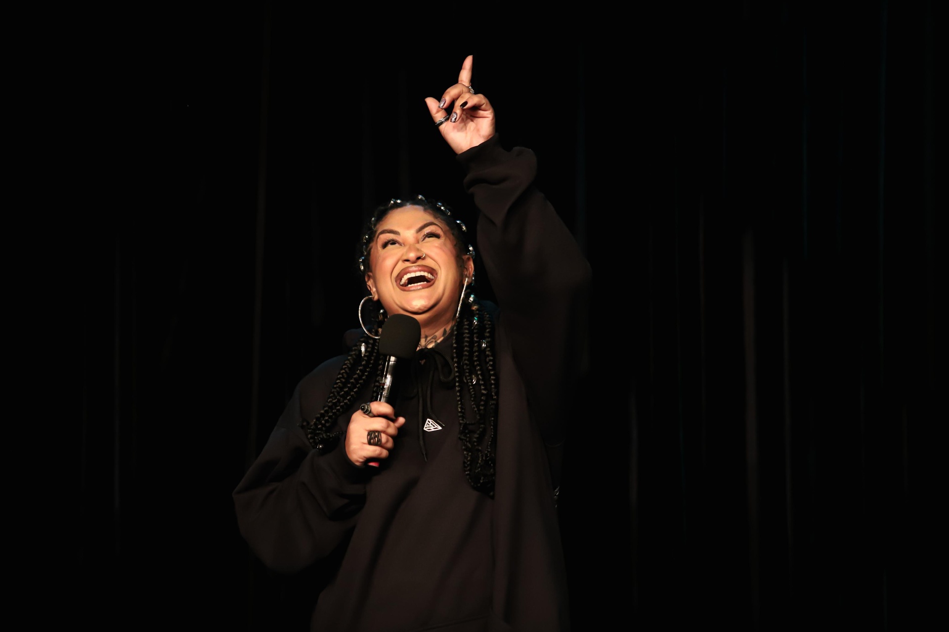 Niny rindo no palco apontando para cima